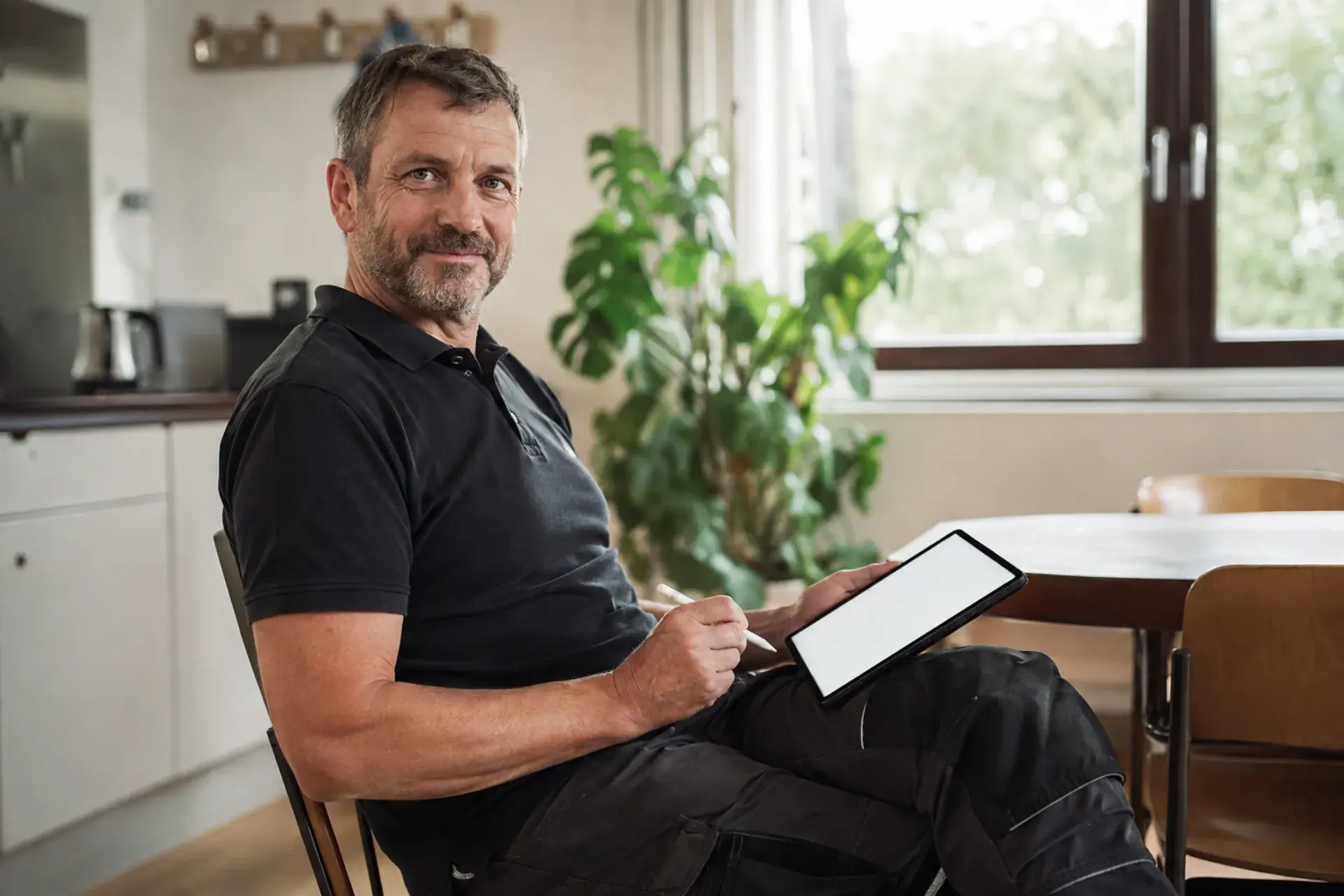 Inhaber eines Elektrobetriebs mit Tablet im Pausenraum